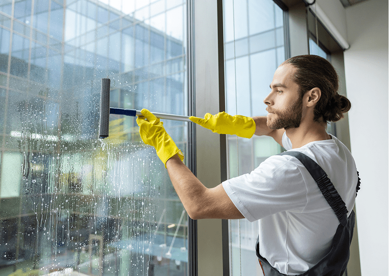 Worker in yellow gloves cleans window