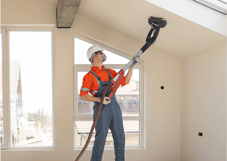 Man in safety gear sanding ceiling