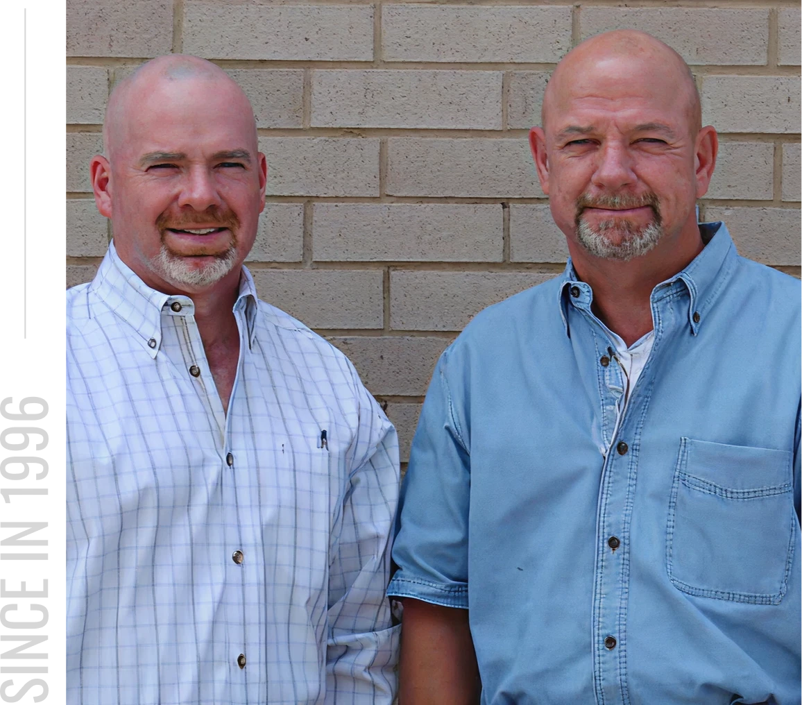 Two men standing against brick wall